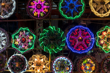 Brightly colored Parols for sale at a stand at nighttime. A Filipino ornamental lantern displayed...