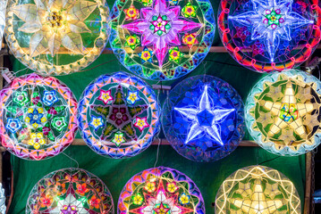 Brightly colored Parols for sale at a stand at nighttime. A Filipino ornamental lantern displayed during the Christmas season. Illuminated with LED light strips.