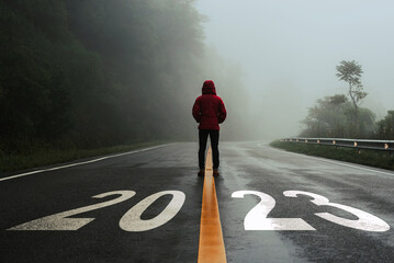 Man standing alone on the road and looking at target with text 2023 written on the road in the...