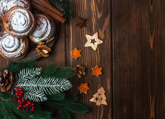 Scones on a plate with cinnamon and walnuts on a wooden background with fir branches, wooden toys and other elements. Top view. New Year Christmas.