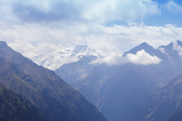 Mountain summer landscape. Snowy mountains and green grass. Peak Karakol Kyrgyzstan. Beautiful view from the top of the mountain