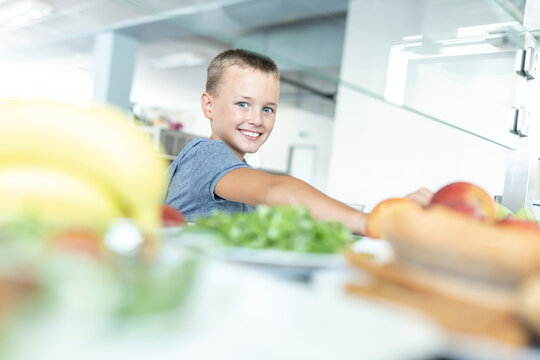 Smiling boy taking food at break time in cafeteria