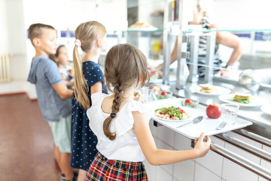 Students standing side by side taking lunch in school cafeteria