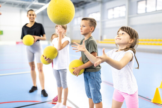 Elementary students playing with ball at school sports court