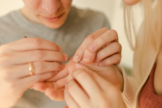 Man Removing Splinter From Woman's Hand At Home