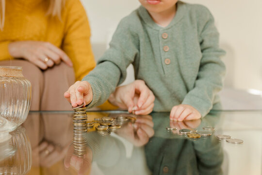 Mother with son counting coins on table at home