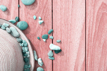 Fototapeta na wymiar Wooden surface with straw ladies hat and scattered turquoise pebbles. Summer vacation backgrounds with copy space