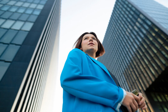 Businesswoman wearing blue blazer standing near office building