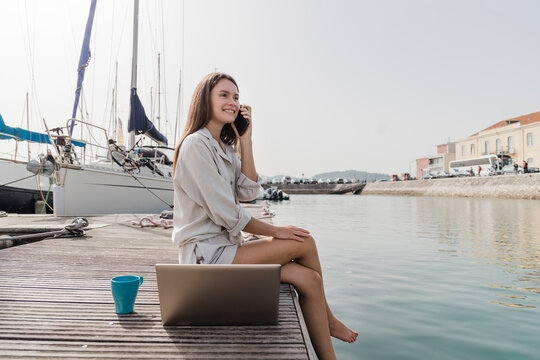 Happy woman talking on smart phone at jetty