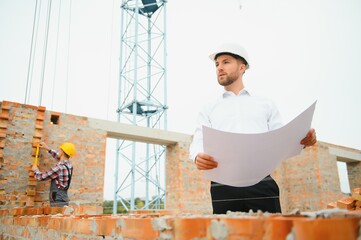 Architect at a construction site with blueprints.