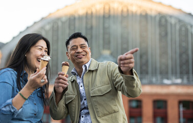 Happy mature couple holding ice cream in front of building