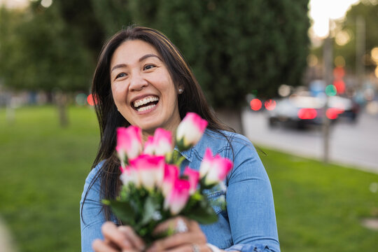 Happy mature woman holding flowers in park on Valentine's day