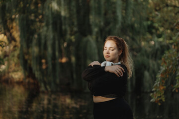 Woman with eyes closed hugging self in park