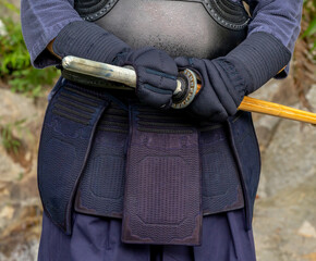 Detail Portrait of kendoka man in the forest holding the sinai-sword.  Kendo is the Japanese martial art of sword fighting