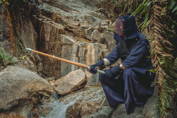 Portrait of kendoka man in a rocky background holding the sinai-sword..  Kendo is the Japanese martial art of sword fighting