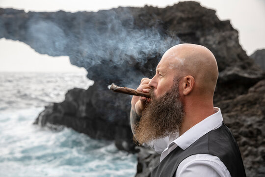 Mature man smoking cigar in front of rock