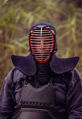 Portrait of kendoka man in the forest..  Kendo is the Japanese martial art of sword fighting
