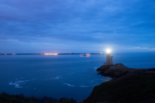 France, Brittany, Plouzane, Petit Minou Lighthouse glowing at cloudy dusk