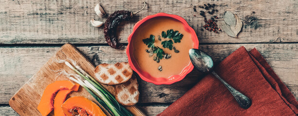 Pumpkin soup on wooden table, linen cloth, vintage cutlery.