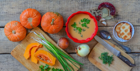 Pumpkin soup on wooden table, linen cloth, vintage cutlery.