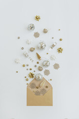 Christmas craft paper envelope with Christmas tree decorations, balls, golden stars, ribbons, tinsel on white background. Flat lay, top view