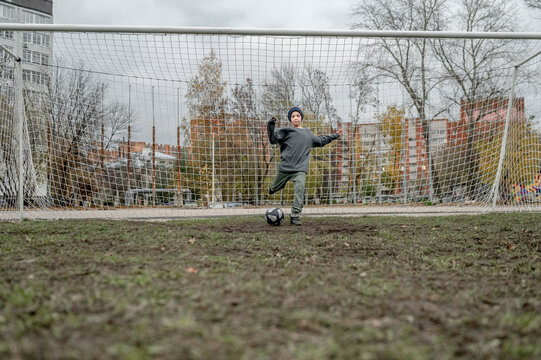 Boy kicking ball in front of goal post at sports field