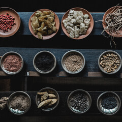 Various spices displaied on small ceramic and metal plates on black wooden background