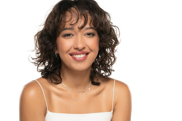 Young dark skinned smiling woman with makeup and wavy hair posing on a white studio background