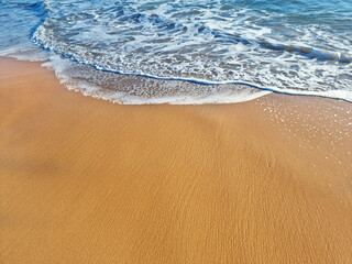Ocean foam covering beautiful sandy beach. Closeup.