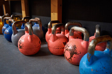 Naklejka na ściany i meble Row of colorful kettlebells in gym. Equipment for sport exercises. Sport activity and healthy lifestyle concept