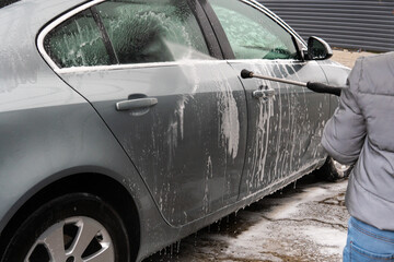 A guy washes a car at a self-service car wash