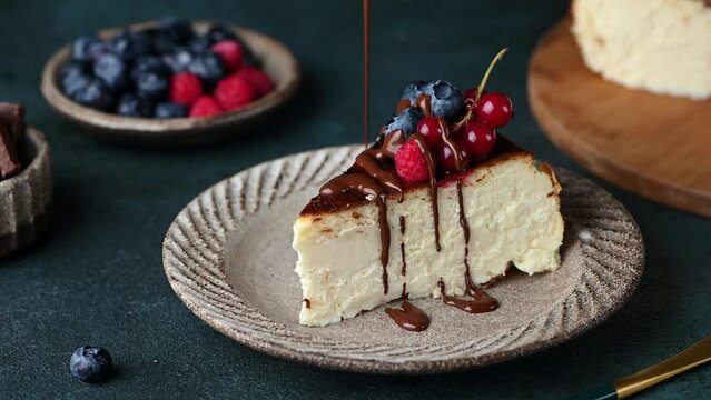 Pouring chocolate on cheesecake. Piece of San Sebastian Basque Cheesecake with berries. Basque cheesecake. Popular dessert. Burnt cheesecake.