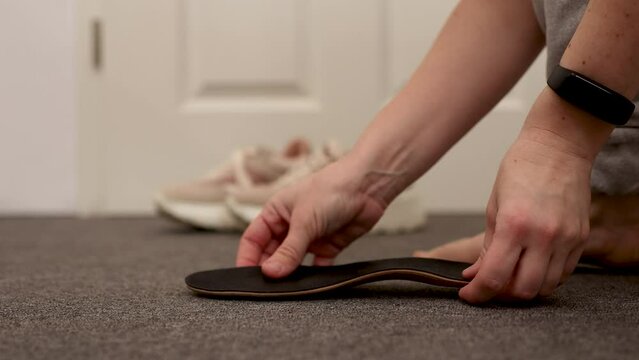 Womans foot and insoles at home, close up view. Flat feet diagnosis and orthotics, shoe inserts. Problems with flatfoot, pain. Identification of flat foot. Treatment to plantar fasciitis.