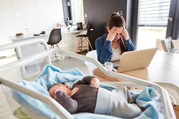 Erschöpfte Mutter im Home Office und schlafendes Baby