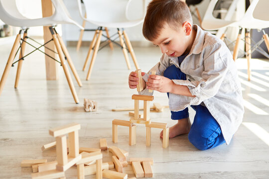 Kleiner Junge baut einen Turm aus Holz Bauklötzen