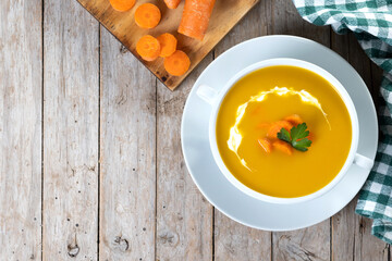 Carrot soup with cream and parsley on wooden table. Top view. Copy space