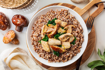 Boiled buckwheat with mushrooms porcini, turkey meat, spinach. Dinner table top view, healthy food concept.