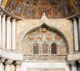 Beautiful architecture attraction of famous symbolic Catholic church exterior in Venice, Italy.  St. Mark's Basilica ornate detail, historical medieval art facade, and sculpted column and artwork.