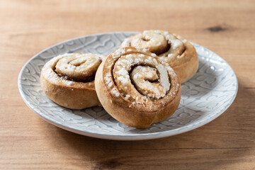 Obraz na płótnie Canvas Cinnamon rolls buns on wooden table. Kanelbulle Swedish dessert