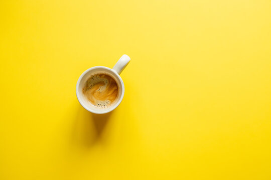 
simple minimalism image of a cup of coffee on a yellow background. top view. copy space. flat lay