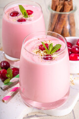 Healthy winter Christmas drink, cranberry oatmeal smoothie of yogurt, with fresh cranberries on beige tiled table, copy space