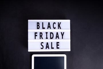 Black friday sale background. Simple black flat lay with sign "Black friday", gift boxes, shopping cart, laptop, tablet, headphones top view copy space. Online Black friday shopping concept