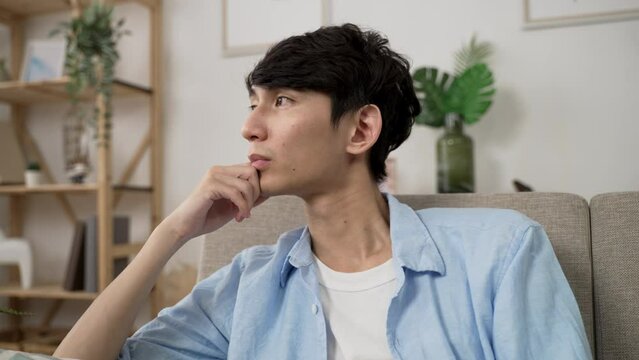 shoulder shot Korean man slowly opening eyes and staring into empty area in distance, feeling solitude after waking up from nap with hand propping face at home