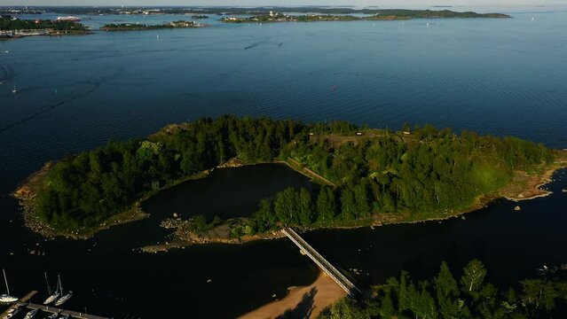 Aerial view overlooking the East Pihlajasaari island, summer evening in Finland - reverse, drone shot