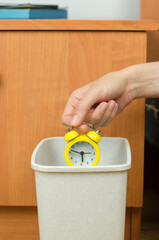 Woman's hand throws the alarm clock into the trash