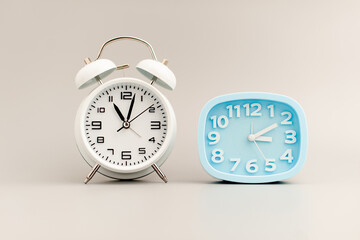 White and blue alarm clock on gray scene, critical time concept.