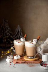 Hot chocolate glass cup with snowman marshmallows. Seasonal, winter or Christmas comfort coffee drinks.