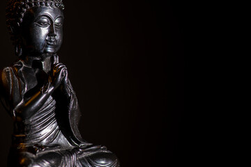 a low key shot of a black buddha statue with black background