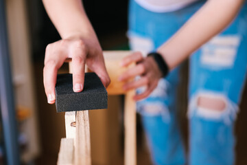 Close-up of two hands of unrecognizable woman sanding a pallet. Home renovation