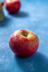 Fresh red apple freslhy picked, on blue background, lifestyle food photo, copy space